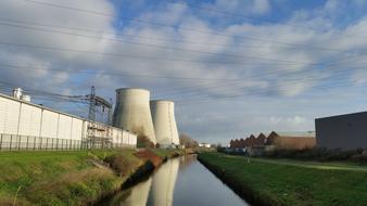 Industrial landscape with the water among the colorful plants and buildings, under the blue sky with clouds