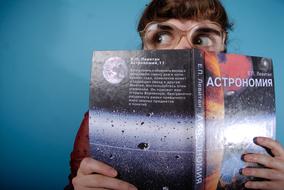photo of a girl in glasses with a book on astronomy