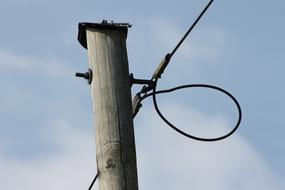 photo of a pole and a black cable against a blue sky