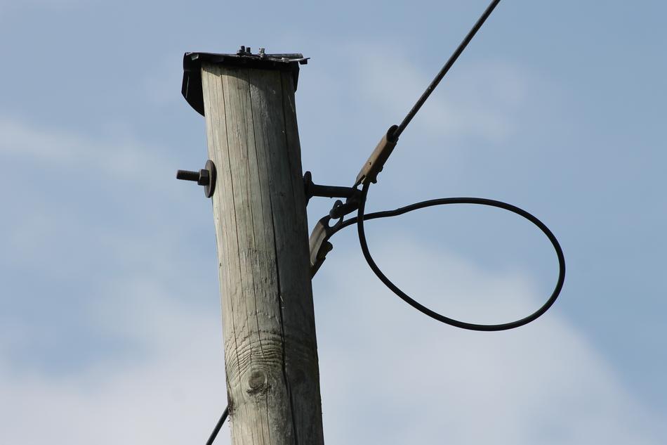 photo of a pole and a black cable against a blue sky