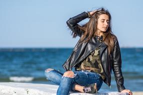 a girl in a leather jacket by the sea