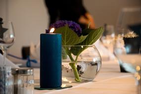 glass vase with a flower and candles on the table
