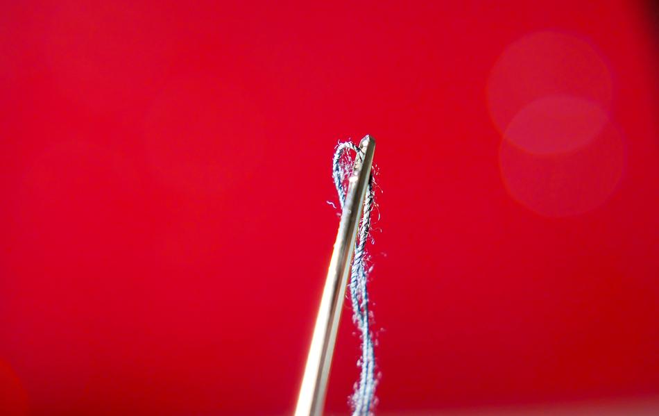 thread with a needle on a red background