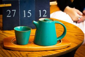 green teapot with a mug on the table
