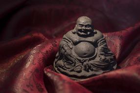 a black buddha in a red blanket