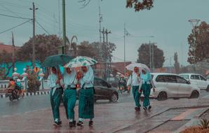 photo of schoolgirls with umbrellas in the rain