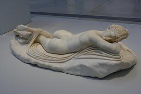 sculpture of a girl lying on a rock