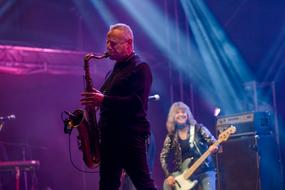man with saxophone and woman with guitar performing on stage, Concert
