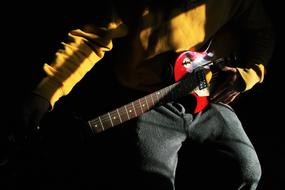 man plays red Electric Guitar, detail