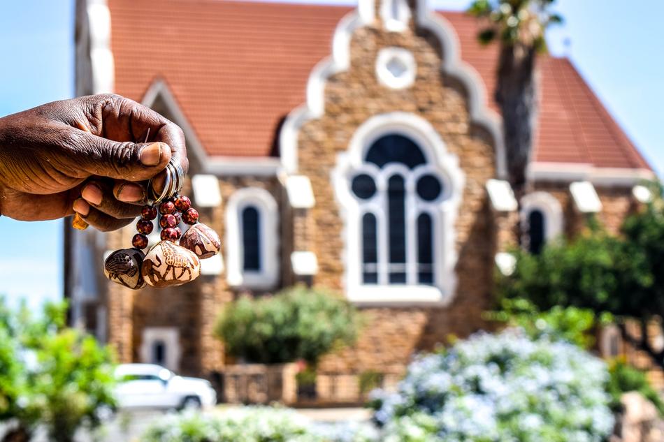 Person holding keyholder, near the building among the plants in Namibia, Africa