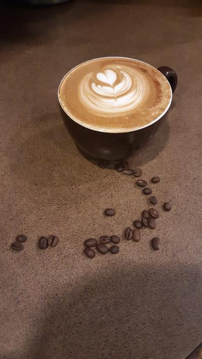 frothy sweet coffee with beans on the table